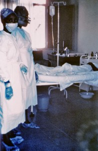 This 1976 photograph shows two nurses standing in front of Ebola case #3, who was treated, and later died at Ngaliema Hospital, in Kinshasa, Zaire. - CDC/Dr. Lyle Conrad